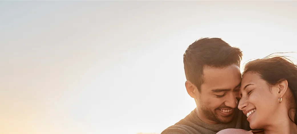Couple embracing and laughing on the beach at sunset